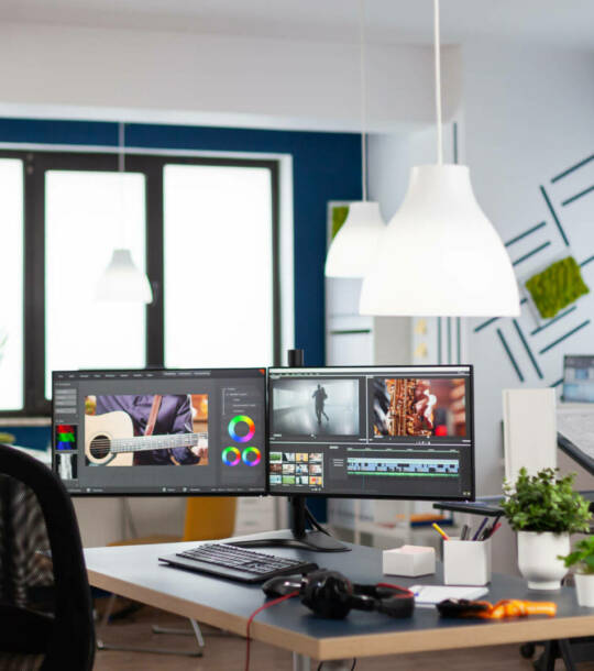 Empty modern creative agency office with dual monitors setup Empty modern creative agency office with dual monitors setup with processing video film montage. Video editing start up studio company with no people in it and post production software on pc displays
